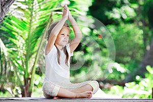 Child doing exercise on platform outdoors. Healthy lifestyle. Yoga girl