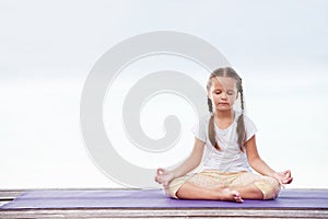 Child doing exercise on platform outdoors. Healthy lifestyle. Yoga girl