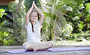 Child doing exercise on platform outdoors. Healthy lifestyle. Yoga girl