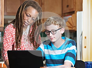 Child doing homework with foster parent in kitchen