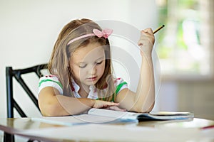 Child doing homework. Kids read and write. photo