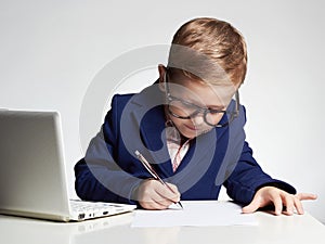 Child doing homework.Young business boy in office.kid in glasses writing pen