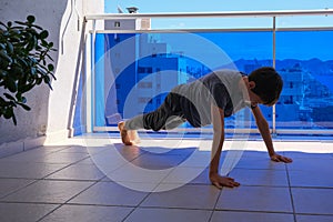 Child doing push-ups sport exercises on balcony. Sport, healhty lifestyle, training, active leisure at home