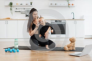 Child doing splits with mother due to online baby yoga class