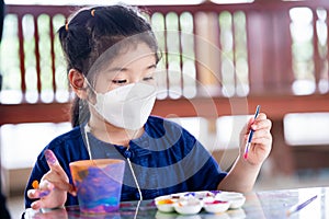 Child doing watercolor art. Kid holding brush. Children paint crafts on clay plant pots.