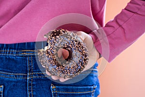 Child with donut behind her back. Cheat meal, unhealthy habits, breaking the diet concept. Copy space