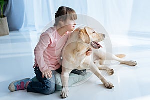 Child with down syndrome and Labrador retriever looking aside