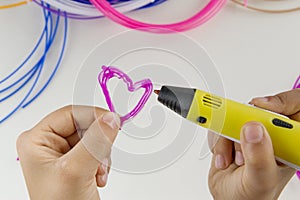 Child draw with 3D pen. Colourful filaments and white background photo