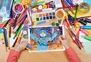 Child drawing astronaut exploring the red planet, space concept, top view hands with pencil painting picture on paper, artwork