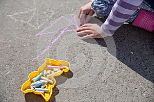 The child drawing a chalk on asphalt