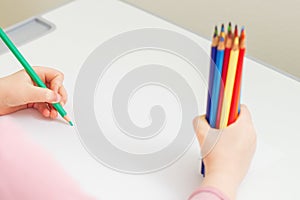 Child is drawing by colored pencils