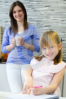 Child drawing with crayons, sitting at table in kitchen