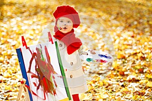 Child drawing on easel in Autumn Park. Creative kids development