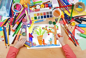 Child drawing rabbit with carrot on kitchengarden near house, top view hands with pencil painting picture on paper, artwork