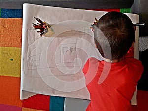 Child drawing a stronghold on a large sheet of paper.