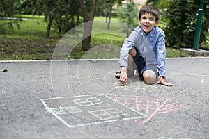 Child drawing sun and house on asphal