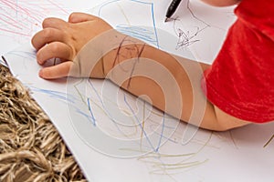 Child drawing on white paper and the hand