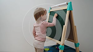 A child draws on a chalkboard at home in a white interior on a white background. Teaching children at home.