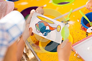 A child draws with colored sand picture. Cartoon characters.