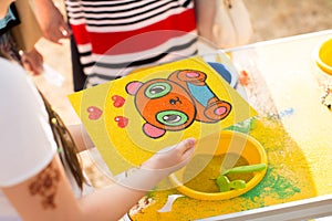 A child draws with colored sand picture. Cartoon characters.