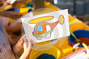 A child draws with colored sand picture. Cartoon characters