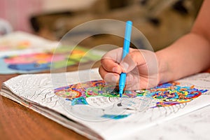 The child draws a felt-tip pen in his album