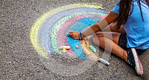 A child draws a rainbow on the asphalt. Selective focus.