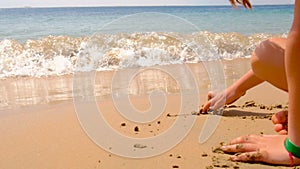 child draws on the sand on the beach. selective focus.