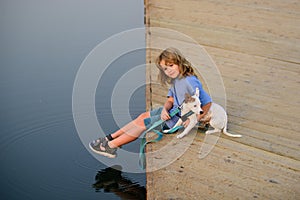 Child dreaming. Happy kid in the park with dog by the lake.