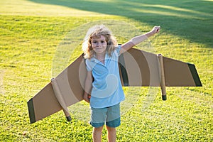 Child dreams of becoming a rocket pilot. Imagination and motivation concept. Kid having fun with toy paper wings.