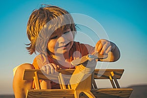 Child dreams of traveling and playing with an airplane pilot aviator. Happy kid playing with toy airplane against blue