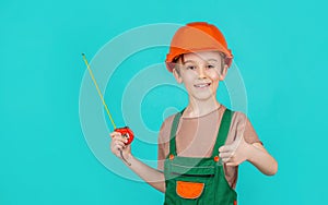 Child dressed as builder with ruller in hands. Child dressed as a workman builder, helmet. Little builder in hardhats