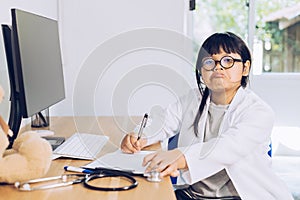 A child dressed as a doctor sits and examines a teddy bear in the hospital