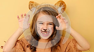 A child dressed up as a tiger with a painted face and ears growls making gestures with his hands. A girl in the form of an animal