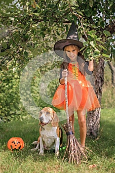 A child dressed up as a witch with his faithful dog friend on Halloween eve