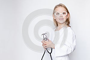 Child dressed up in doctor uniform with toy eyeglasses holding stethoscope, looking at camera, half lenth portrait, copy space