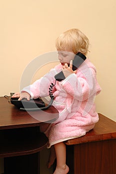 The child in a dressing gown calls by phone