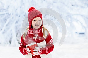 Child drinking chocolate on Christmas in snow
