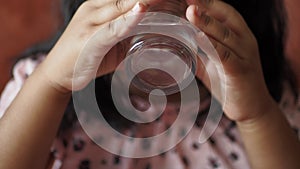 child drinking glass of water sitting on sofa