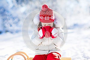 Child drinking hot chocolate in winter park. Kids in snow on Christmas.