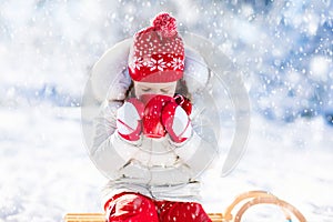 Child drinking hot chocolate in winter park. Kids in snow on Christmas.