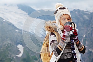 Child drinking tea in thermos in mountains