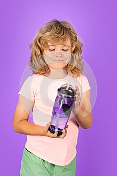 Child drinking water, isolated on studio background. Kid enjoy pure fresh mineral water. Thirsty kid hold glass aqua