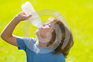 Child drinking water. Kid enjoy pure fresh mineral water. Outdoor kid boy drinking pure bottle from glass. Close up
