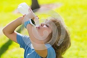 Child drinking water. Kid enjoy pure fresh mineral water. Outdoor kid boy drinking pure bottle from glass. Close up