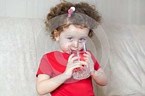 Child drinks clean water from a glass. beautiful little girl quenches thirst.