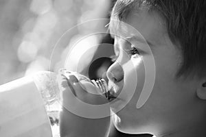 Child drinks water from a bottle while walking, baby health. Boy bottle of water. Young boy holding drink fresh water