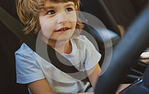 Child driver. Cute child boy while driving car as driver. Baby kid sitting in seat.