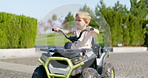 A child driving a toy electric car in a park on a summer day