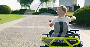A child driving a toy electric car in a park on a summer day